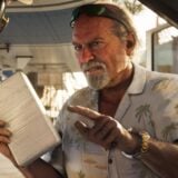 A man points his finger menacingly while holding a paper.