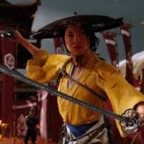 Atsu holds up two swords ready to fight.