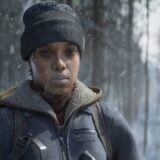 A woman stands in the cold hunting a deer.