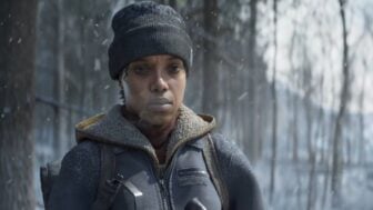 A woman stands in the cold hunting a deer.