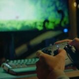 A player hold a Steam Controller in front of a PC.