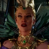 A woman wearing a feathered costume looks confused.