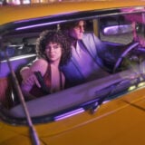 A man and a woman appear in a car together.