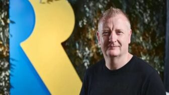Craig Duncan poses in front of a Rare logo.