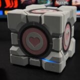 A Companion Cube sits on a desk.
