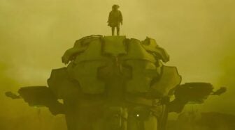 A figure stands on a robot in a sandstorm.