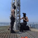 Two people appear on top of a skyscraper.