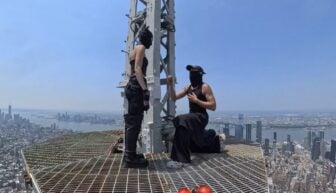 Two people appear on top of a skyscraper.