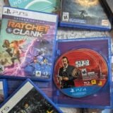 PlayStation game discs and boxes sit on a floor.